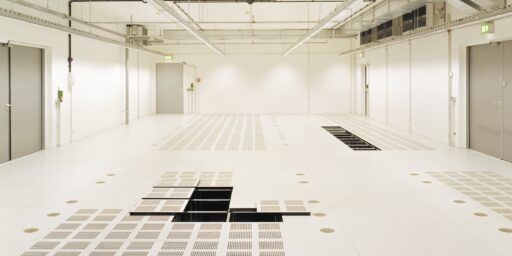 Stort teknisk rom med perforerte paneler i datagulv og åpne moduler for tilgang til installasjoner.