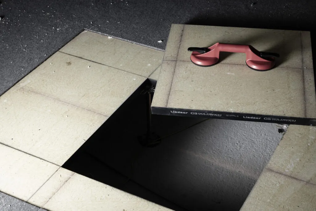 Åpnet installasjonsgulv med gulvplate og sugekopp som viser underliggende teknisk installasjon.