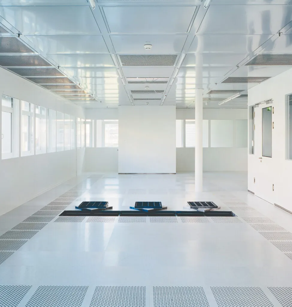 Raised Access Floor in a bright technical room with open floor modules showing concealed service routing beneath the floor.