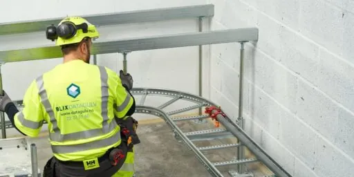 Blix Datagulv-montør monterer kabelbro og rammesystem langs vegg under installasjon av installasjonsgulv