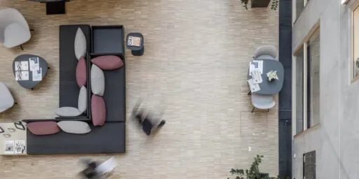 Installasjonsgulv med åpnet gulvmodul som viser teknisk føringsvei i et moderne rom med betongvegg og tregulv.