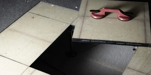 Åpnet installasjonsgulv med gulvplate og sugekopp som viser underliggende teknisk installasjon.